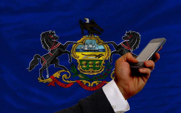 Teléfono celular frente a la bandera del estado americano de Pensilvania — Foto de Stock