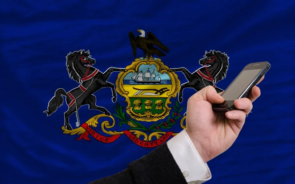Teléfono celular frente a la bandera del estado americano de Pensilvania —  Fotos de Stock