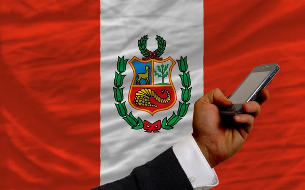 Мобильный телефон перед национальным флагом Перу — стоковое фото