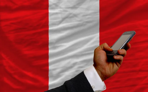 Teléfono celular frente a bandera nacional de perú — Foto de Stock