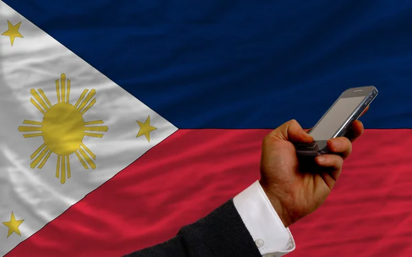 Téléphone portable devant le drapeau national des philippines — Photo