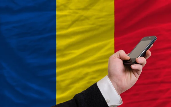 Мобильный телефон перед национальным флагом Румынии — стоковое фото