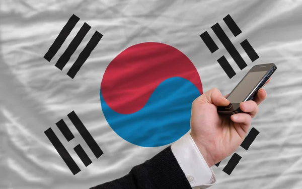 Мобильный телефон перед национальным флагом Южной Кореи — стоковое фото