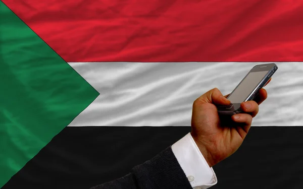 Cell phone in front national flag of sudan — Stock Photo, Image