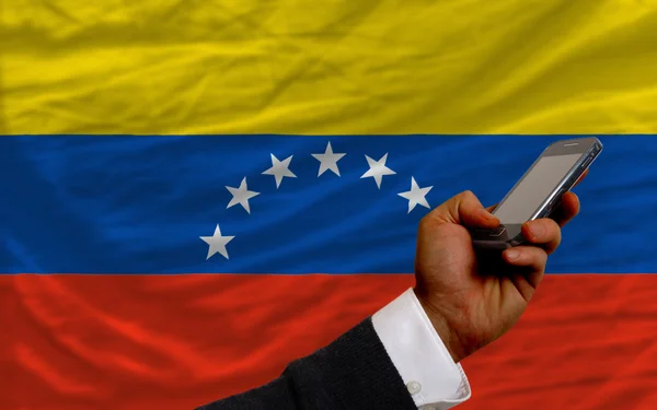 Mobiele telefoon in front nationale vlag van venezuela — Stockfoto