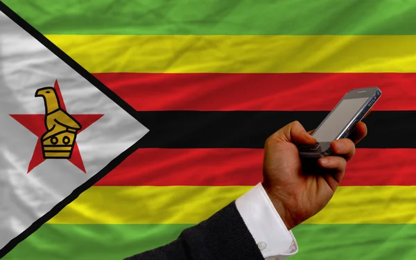 Cell phone in front national flag of zimbabwe — Stock Photo, Image