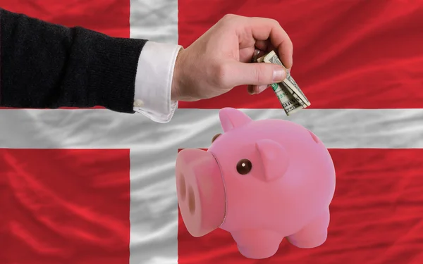 Dollar in piggy rijke bank en de nationale vlag van Denemarken — Stockfoto