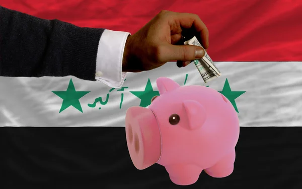Dollar into piggy rich bank and national flag of iraq — ストック写真