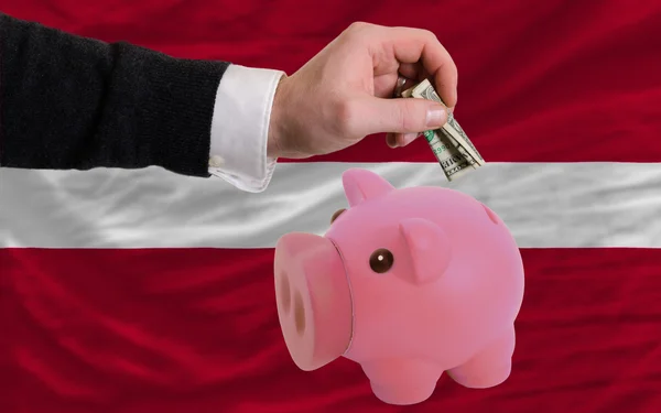 Dollar in piggy rijke bank en de nationale vlag van Letland — Stockfoto