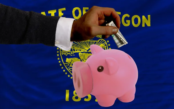 Dollar in piggy rijke bank en vlag van Amerikaanse staat van orego — Stockfoto