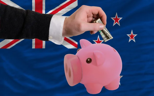 Dollar into piggy rich bank and national flag of new zealand — Stock Photo, Image