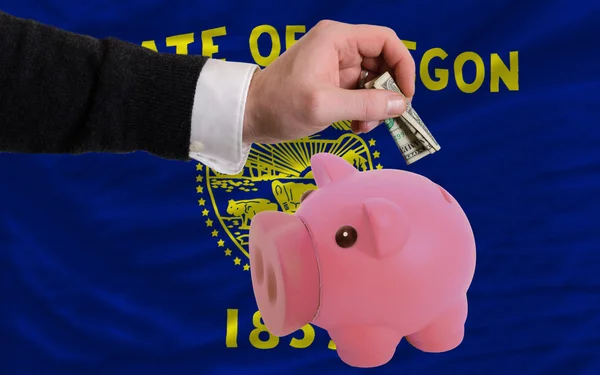 Dollar in piggy rijke bank en vlag van Amerikaanse staat van orego — Stockfoto