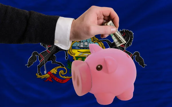 Dollar in piggy rijke bank en de vlag van de Amerikaanse deelstaat penns — Stockfoto