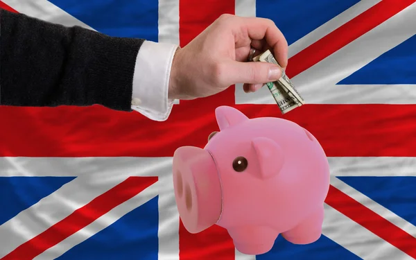 Dollar into piggy rich bank and national flag of united kingdom — Stock Photo, Image