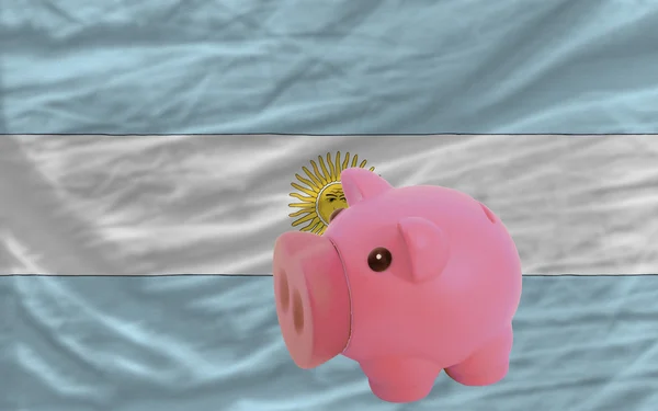 Piggy rijke bank en de nationale vlag van Argentinië — Stockfoto