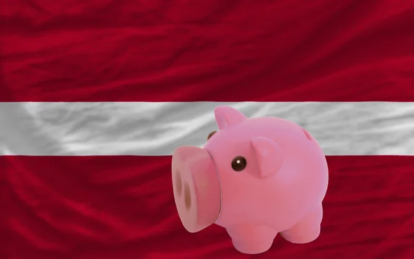 Piggy rijke bank en de nationale vlag van Letland — Stockfoto