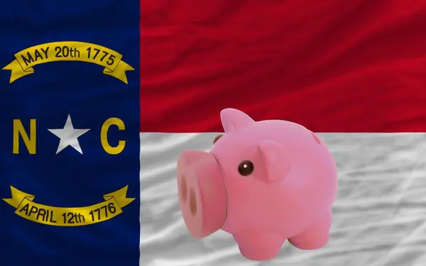 Piggy rijke bank en de vlag van de Amerikaanse staat north carolina — Stockfoto