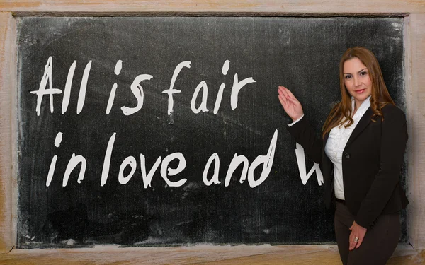Teacher showing All is fair in love and war on blackboard — Stock Photo, Image