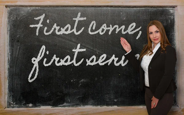 Teacher showing First come, first served on blackboard — Stock Photo, Image