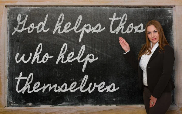 Teacher showing God helps those who help themselves on blackboar — Stock Photo, Image