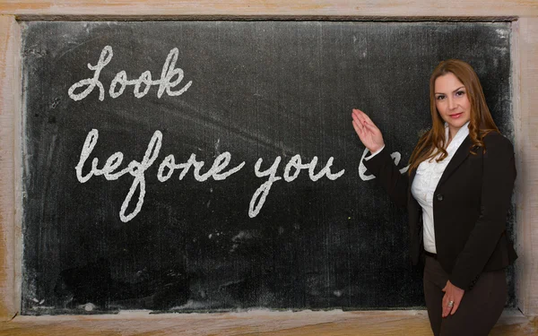 Teacher showing Look before you leap on blackboard — Stock Photo, Image