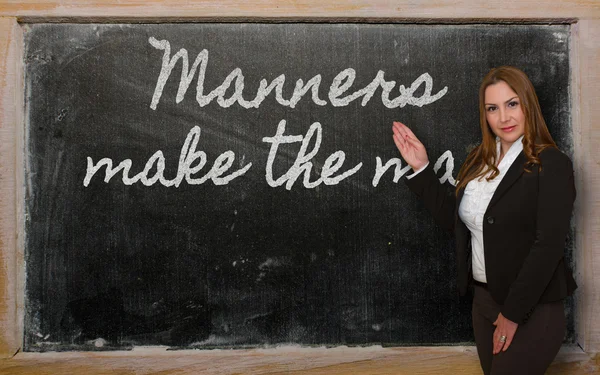Teacher showing Manners make the man on blackboard — Stock Photo, Image