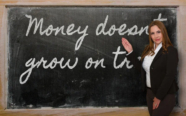 Teacher showing Money doesn t grow on trees on blackboard — Stock Photo, Image