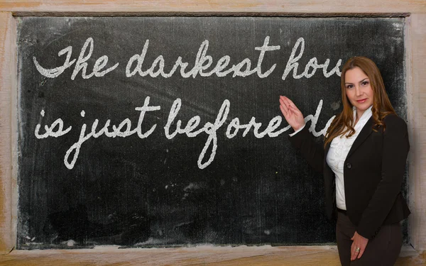 Teacher showing The darkest hour is just before dawn on blackboa — Stock Photo, Image