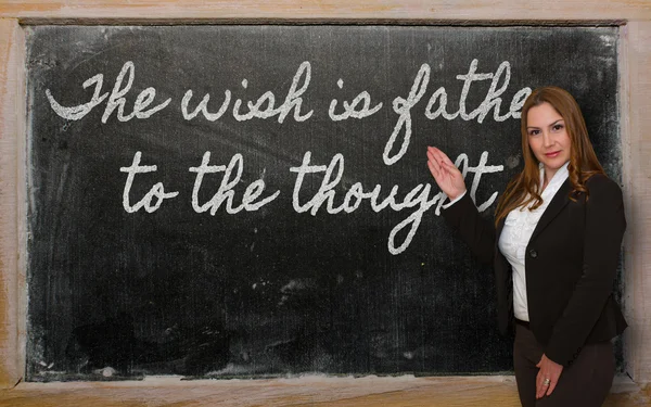 Teacher showing The wish is father to the thought on blackboard — Stock Photo, Image