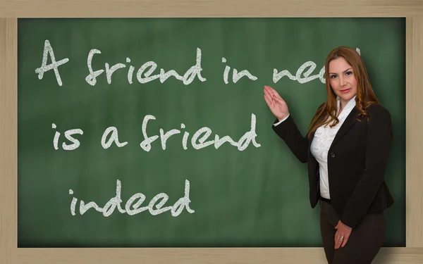 Teacher showing A friend in need is a friend indeed on blackboar — Stock Photo, Image