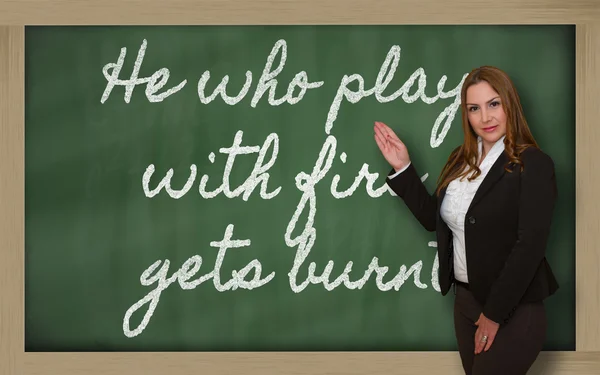 Teacher showing He who plays with fire gets burnt on blackboard — Stock Photo, Image