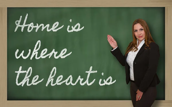 Teacher showing Home is where the heart is on blackboard — Stock Photo, Image