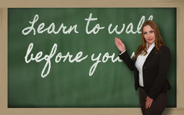 Teacher showing Learn to walk before you run on blackboard — Stock Photo, Image
