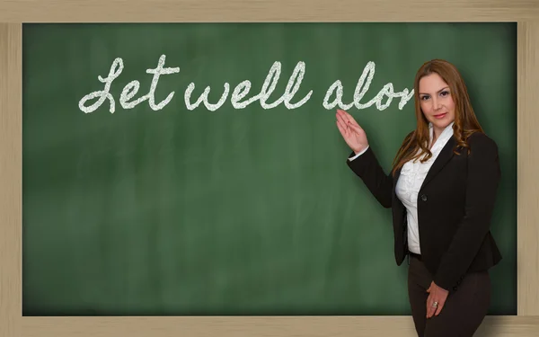 Teacher showing Let well alone on blackboard — Stock Photo, Image