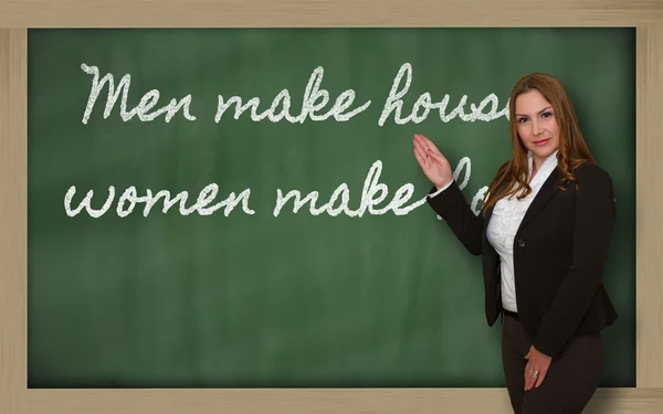 Teacher showing Men make houses, women make homes on blackboard — Stock Photo, Image