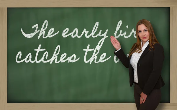 Teacher showing The early bird catches the worm on blackboard — Stock Photo, Image