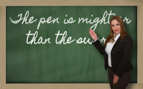 Insegnante che mostra La penna è più potente della spada sulla lavagna — Foto Stock