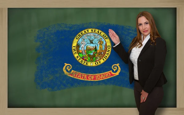 Teacher showing flag of idaho on blackboard for presentation mar — Stock Photo, Image