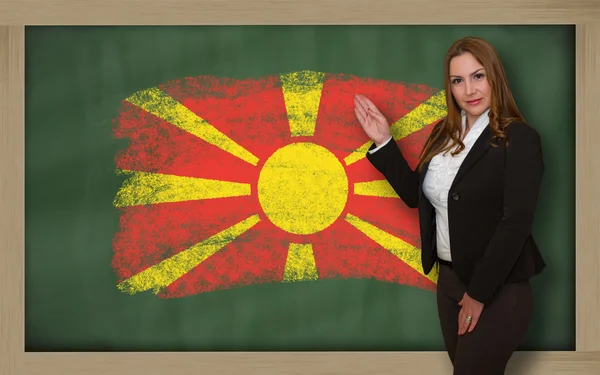 Teacher showing flag ofmacedonia on blackboard for presentation — Stock Photo, Image