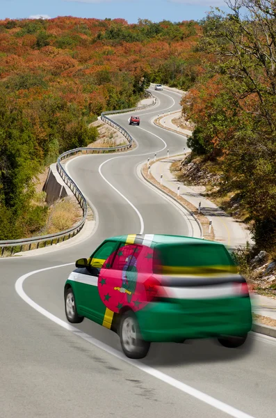 Автомобиль на дороге в национальном флаге Доминики цветов — стоковое фото