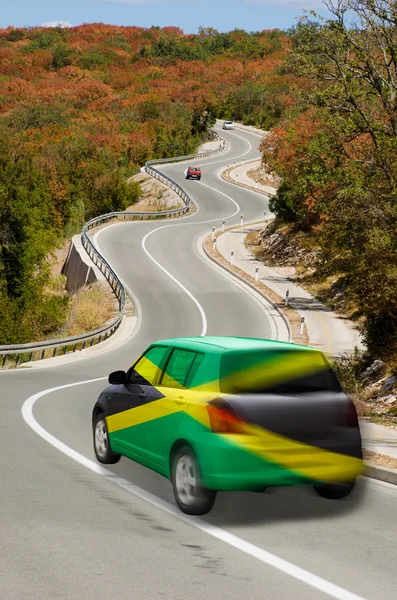 Автомобиль на дороге в национальном флаге Ямайки цветов — стоковое фото