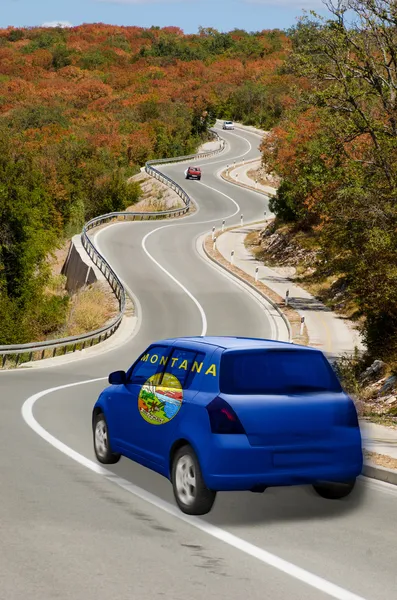 Car on road in flag of american state of montana colors — Stock Photo, Image