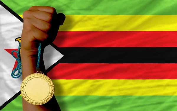 Medalha de ouro para esporte e bandeira nacional de zimbabwe — Fotografia de Stock