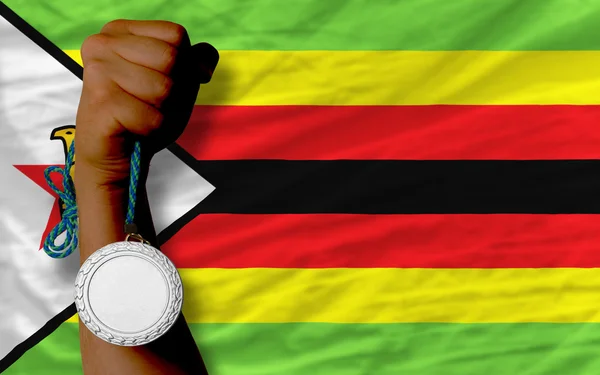Medalha de prata para esporte e bandeira nacional de zimbabwe — Fotografia de Stock