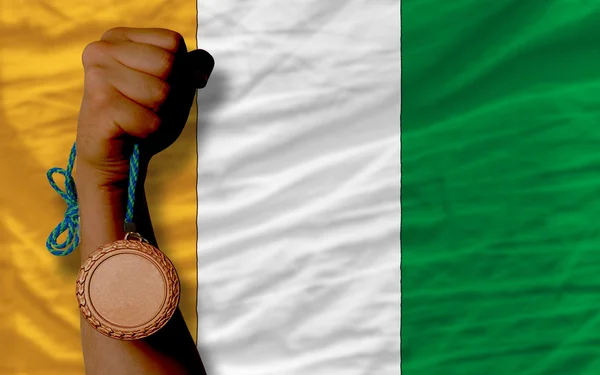 Бронзова медаль за спорт і національний прапор Коте-Івору — стокове фото