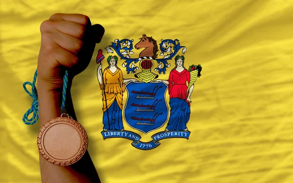 Bronze medal for sport and flag of american state of new jersey — Stock Photo, Image