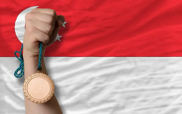 Medalha de bronze para esporte e bandeira nacional de singapore — Fotografia de Stock