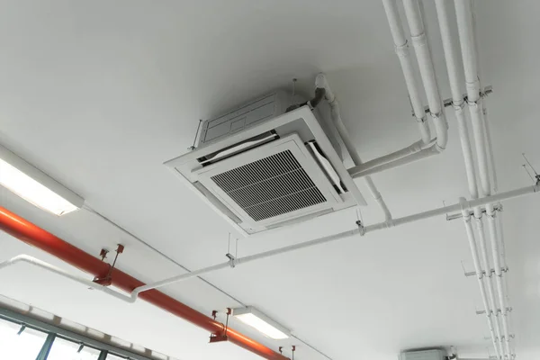 Modern white ceiling mounted cassette type air conditioner in office building system work. Ventilation compressor.