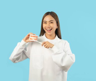 Mutlu Asyalı dişçi kadın portresi, hastane kliniğinde gülümseyen, dişlerini fırçalayan insanlar. Doktor mavi ile izole edilmiş. Diş hekimliği. Tıbbi ve diş sağlığı.