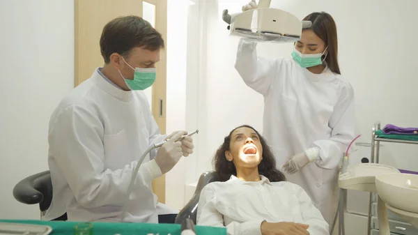 病院の診療所で歯科口腔鏡を使って女性患者の歯を調べる歯科医 歯は歯の道具で調べます — ストック写真
